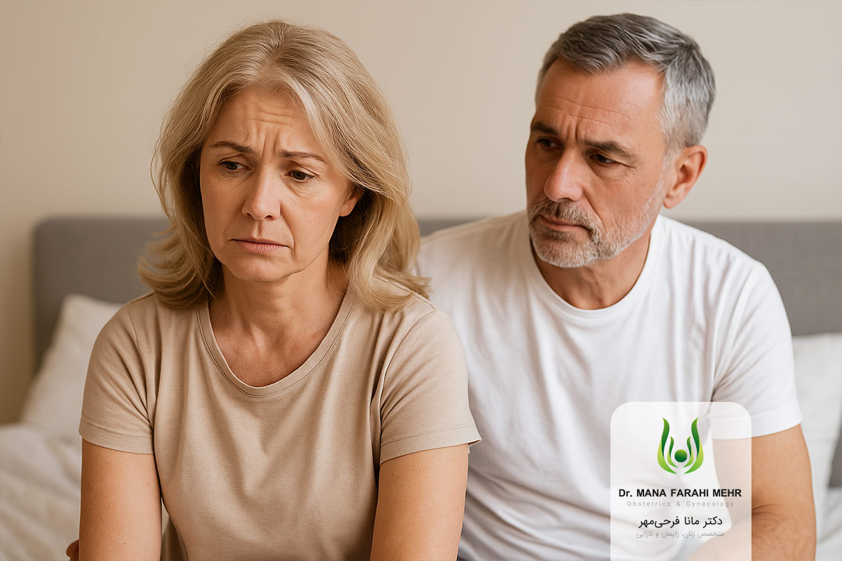 زن میانسال ناراحت روی تخت نشسته و همسرش با نگرانی او را نگاه می‌کند، نمادی از تغییرات جنسی در دوران یائسگی
